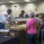 An image of people eating at a buffet table